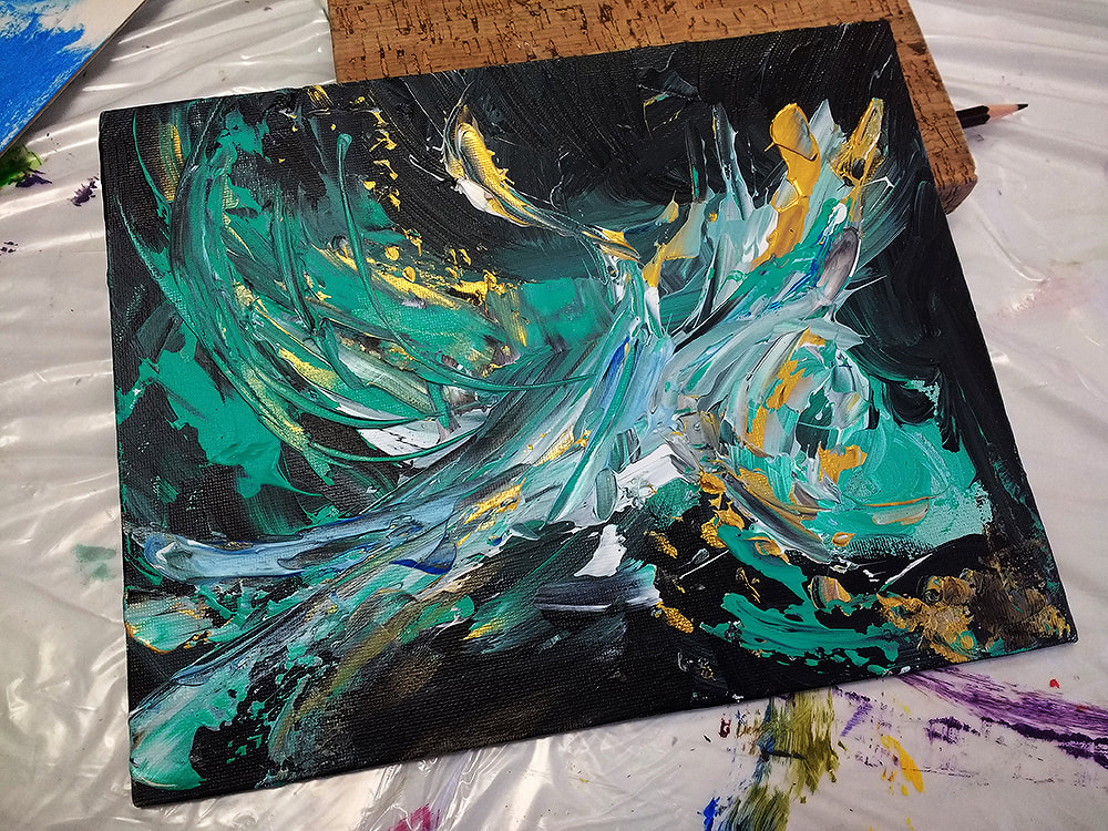 An abstract swirl of mainly teal and gold acrylic paint against a dark background. It vaguely resembles a bird in flight. 